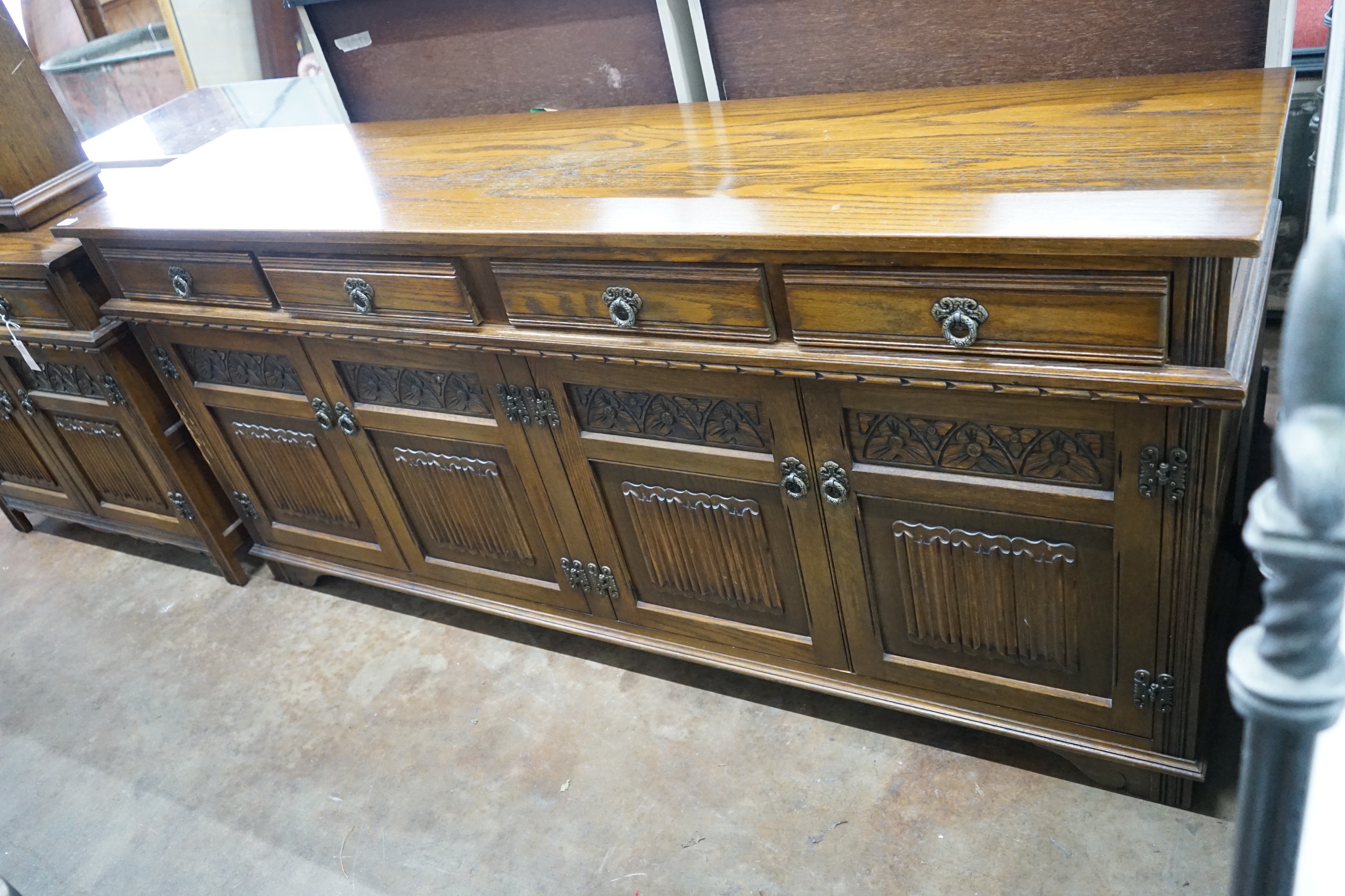 A reproduction 18th century style carved and linen fold moulded oak sideboard width 187cms, depth 44cms, height 87cms.